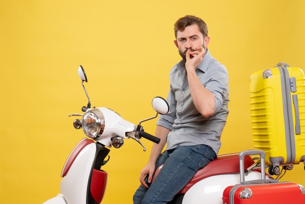 Front view of travel concept with bearded young man sitting on motocycle with suitcases making perfect gesture on it on yellow 