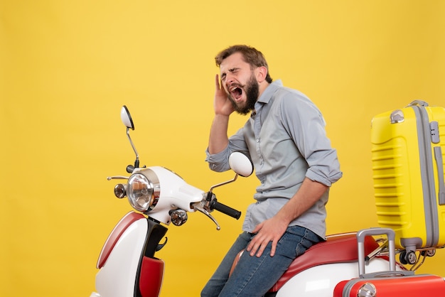 노란색에 외치는 그것에 가방과 motocycle에 앉아 감정적 인 젊은 남자와 여행 개념의 전면보기