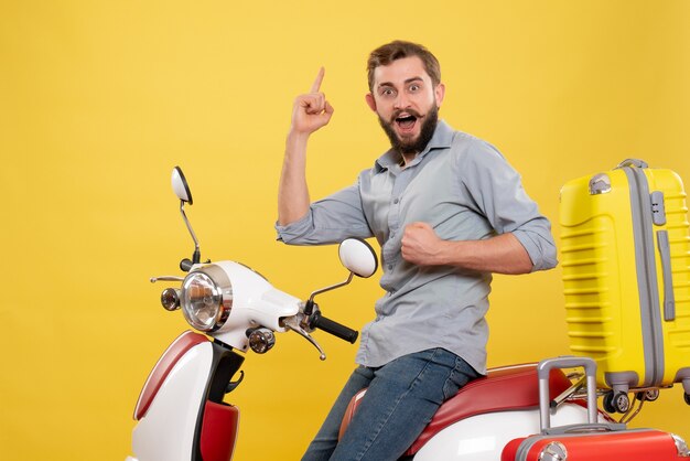 Front view of travel concept with proud ambitious young man sitting on motocycle with suitcases on it on yellow 