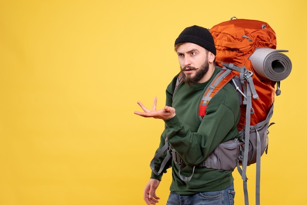Front view of travel concept with wondering emotional young guy with packpack