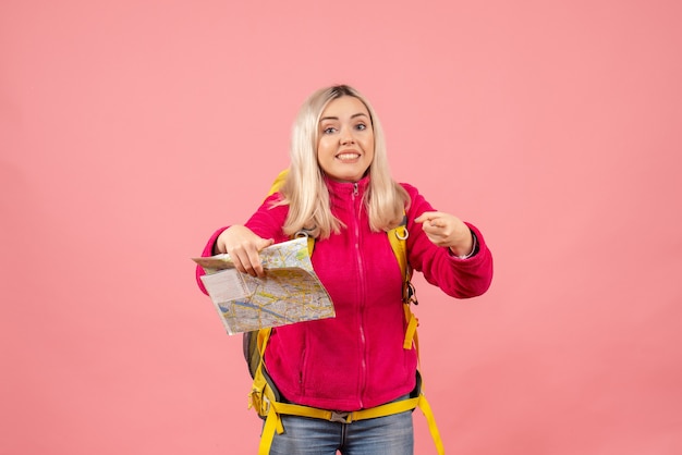 Front view traveler woman in casual clothes wearing backpack holding map pointing