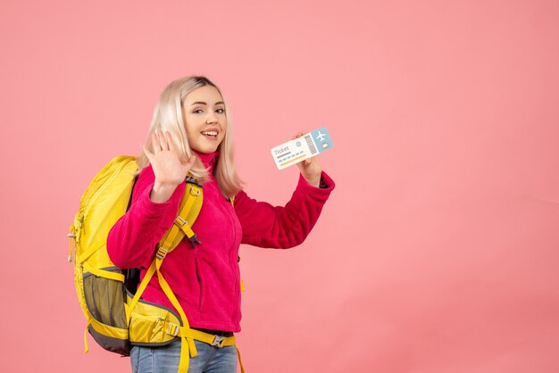 Front view traveler woman with backpack waving hand holding ticket