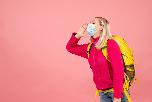 Front view traveler woman with yellow backpack wearing mask calling someone