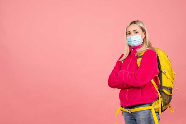 Front view traveler woman with yellow backpack wearing mask crossing hands