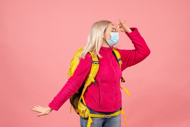 Front view traveler woman with yellow backpack wearing mask holding nose