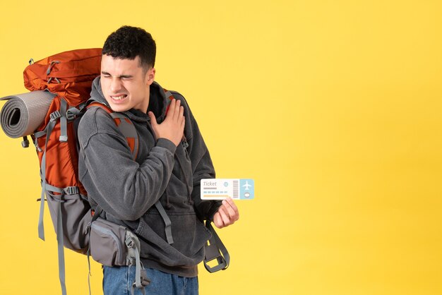 Front view traveller man with backpack holding ticket holding his heart with pain