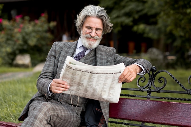 Вид спереди модный зрелый мужчина читает газету