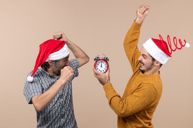 Foto gratuita vista frontale due uomini arrabbiati che entrambi perforano la sveglia su fondo isolato beige