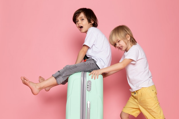 Free photo front view two boys adorable cute sweet playing in white t-shirts on pink desk