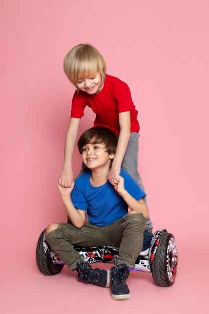 Вид спереди двух мальчиков очаровательны сладкие милые счастливые Segway верхом на розовом полу