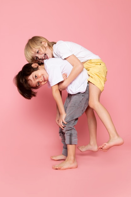 Front view two boys playing with each other in white t-shirt on pink desk