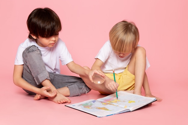 front view two boys in white t-shirts drawing map on pink