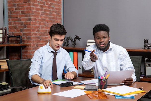 Free photo front view two business partners working in office one of them pointing finger camera