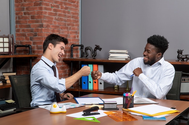 Front view two businessmen fist bump together