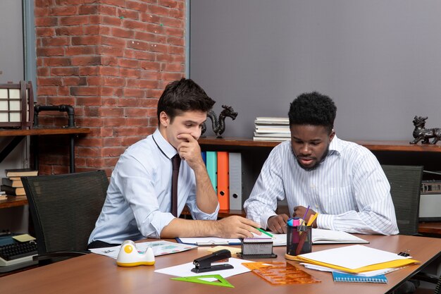 Front view two businessmen sitting at desk working together