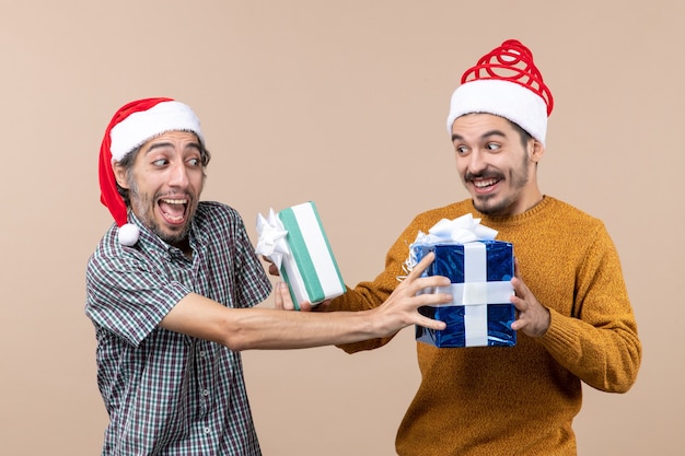 베이지 색 격리 된 배경에 크리스마스 선물을 교환하는 전면보기 두 혼란 남자