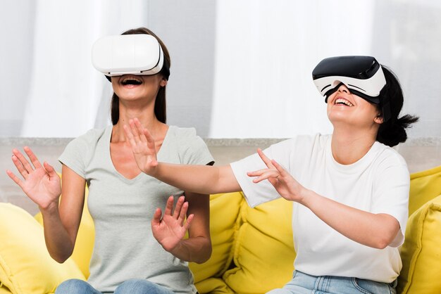 Вид спереди двух друзей дома с помощью гарнитуры виртуальной реальности