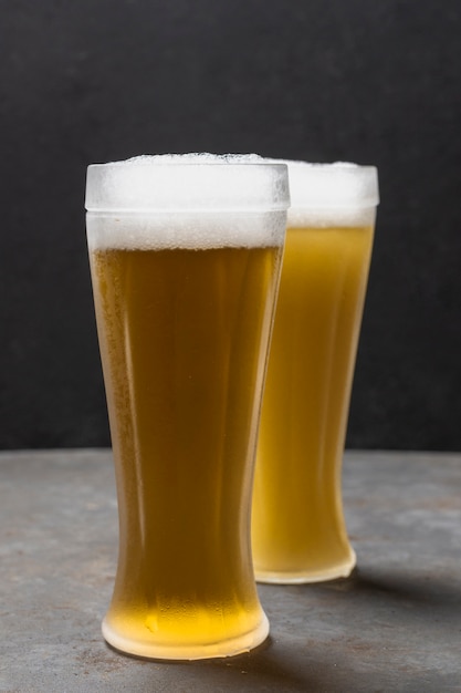 Free photo front view two glasses with beer having foam