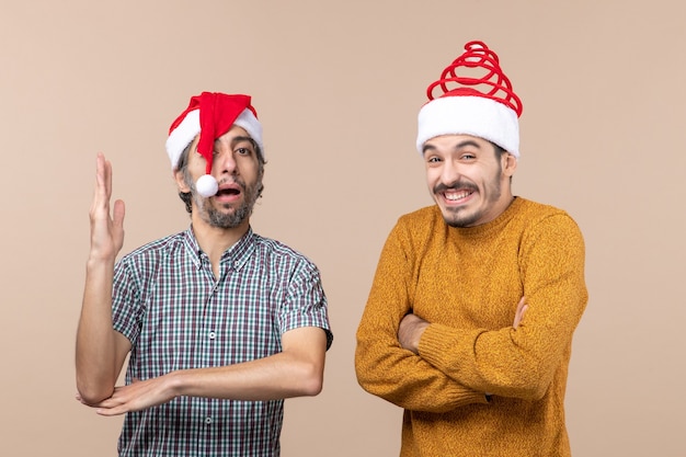 Front view two guys one raising his hand the other laughing on beige isolated background