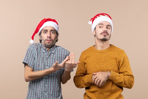 베이지 색 격리 된 배경에 불쾌감을주는 산타 모자와 함께 전면보기 두 남자