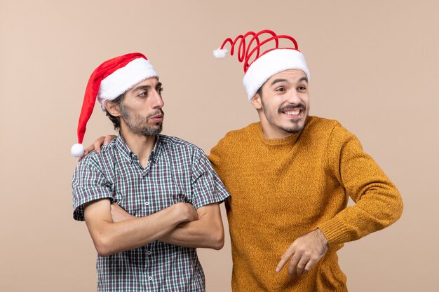 正面図サンタの帽子をかぶった2人の男が他の肩に手を置き、孤立した背景に笑みを浮かべて