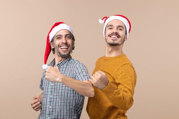 Front view two happy men with santa hats standing with confidence on isolated background