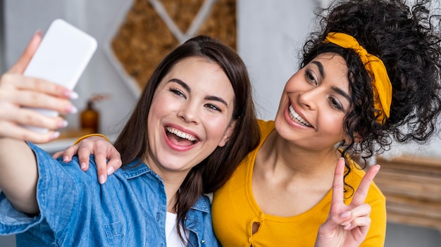 Front view of two happy women laughing and taking selfie