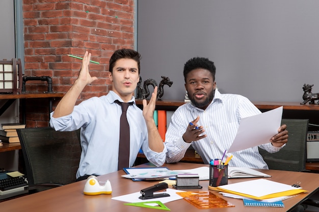 Front view two puzzled businessmen one of them holding paper