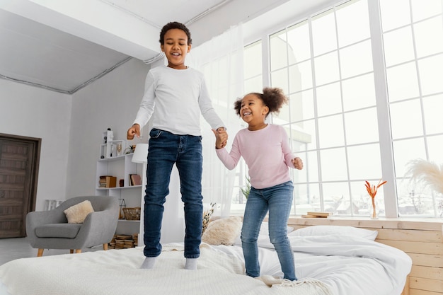 Free photo front view of two siblings jumping in bed at home