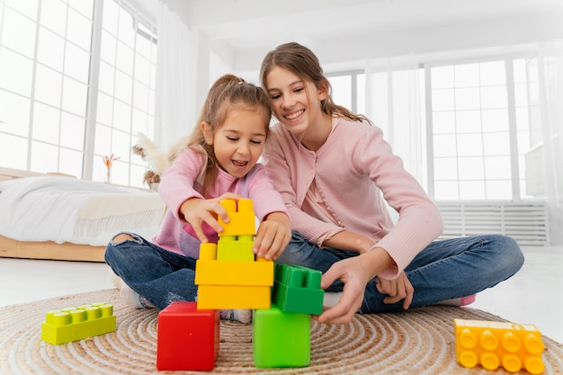 Front view of two sisters playing at home with toys