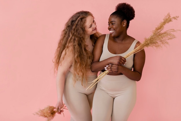 Front view of two smiley women posing while wearing a body shaper