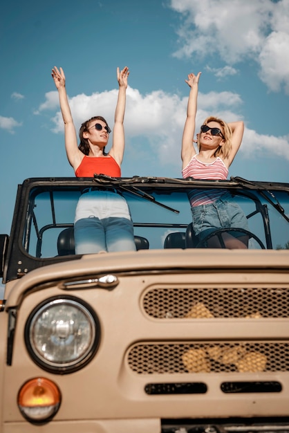 Front view of two women having fun while traveling by car