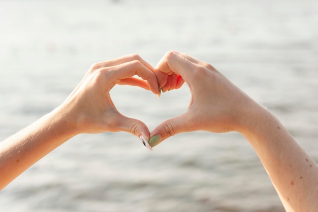 Front view of two women making heart sign with hands
