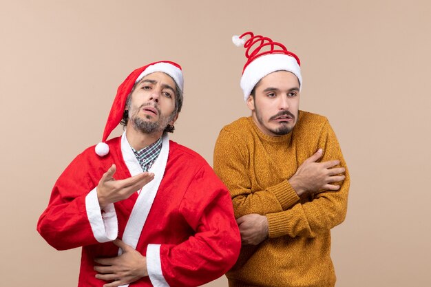 Vista frontale due ragazzi di natale uno con il cappotto di babbo natale ma l'altro congelamento su sfondo beige isolato