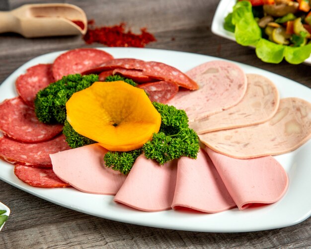 Front view a type of sausage on a plate with herbs and spices on the table