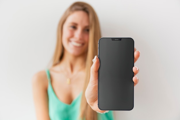 Free photo front view unfocused woman showing her smartphone with empty screen