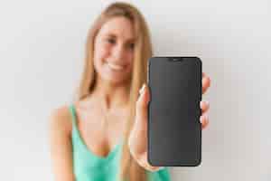 Free photo front view unfocused woman showing her smartphone with empty screen