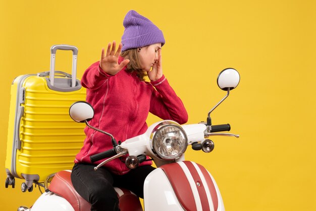 Front view upset young girl on moped making stop sign