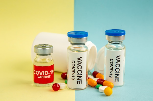 front view vaccine against covid with different pills on yellow-blue background