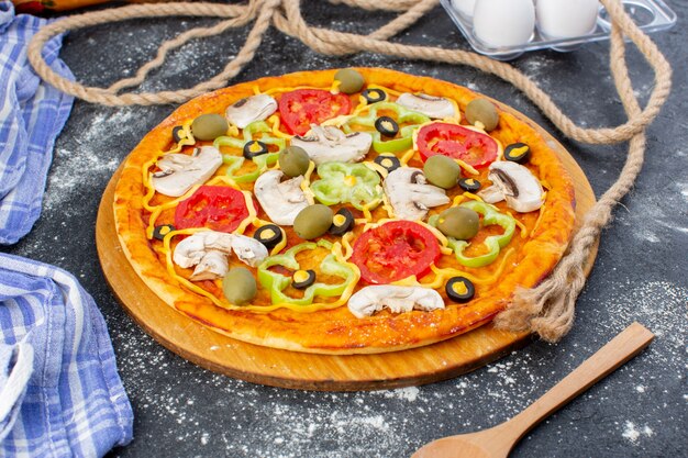 Front view vegetable mushroom pizza with tomatoes olives mushrooms with flour on grey desk pizza dough italian food