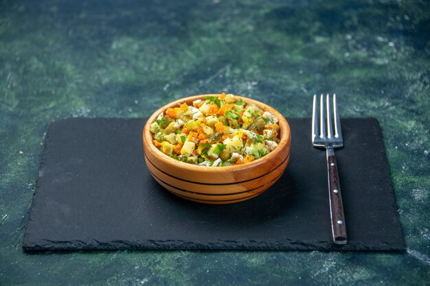 овощной салат из отварных ингредиентов в тарелке на темном фоне, вид спереди