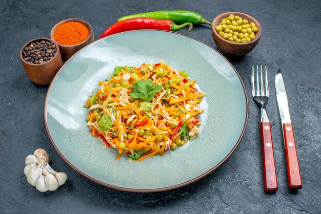 ダークテーブルの調味料と野菜サラダの正面図健康サラダダイエット食品