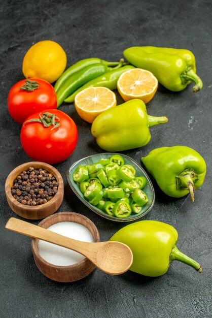 Front view vegetables composition red tomatoes bell-peppers and lemon on dark background meal salad health diet photo food