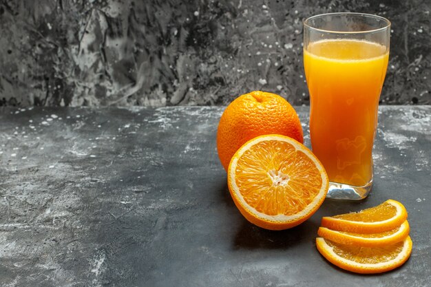 회색 배경에 잘게 잘린 신선한 오렌지와 주스를 자른 비타민 소스의 전면 보기