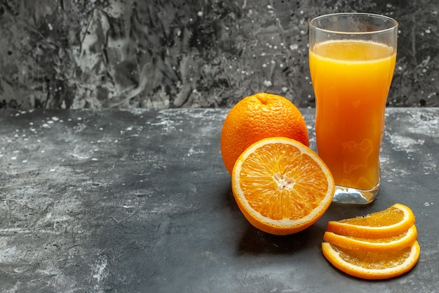 Front view of vitamin source cut chopped and whole fresh oranges and juice on gray background