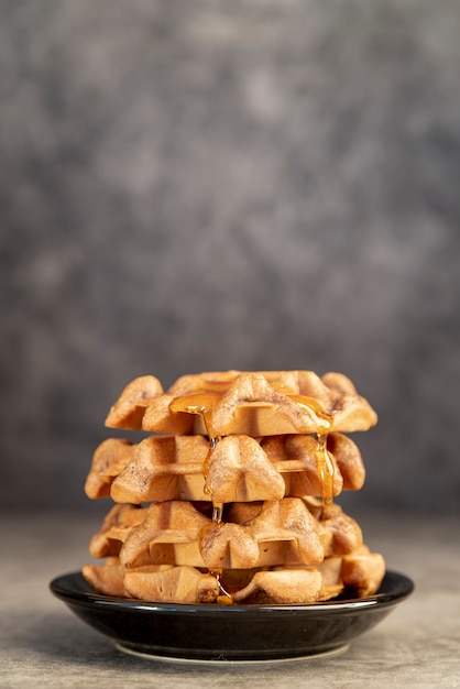 Front view of waffles stacked on plate with honey and copy space