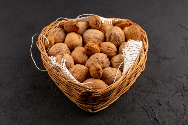 front view walnuts inside brown basket on the dark