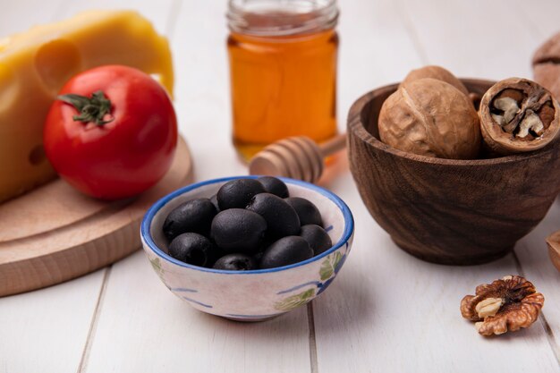 Front view walnuts with tomato  olives  cheese on a stand and honey on a white background