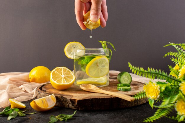 유리에 레몬 신선한 시원한 음료와 함께 전면보기 물 얼음 조각과 레몬 주스를 받고 레몬 슬라이스 레몬 오이 어둠에