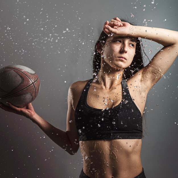 Вид спереди мокрого женского игрока в регби, держащего мяч
